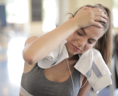 Young woman sweating and resting in a gym after an intense workout session.