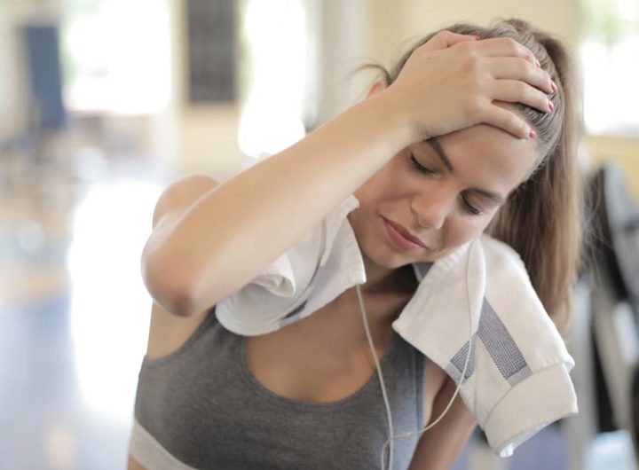 Young woman sweating and resting in a gym after an intense workout session.